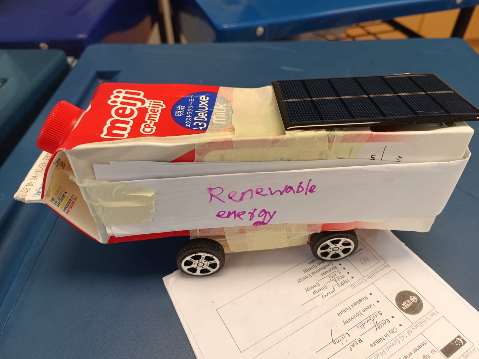 A finished solar bus built on an upcycled Meiji milk carton, labelled "Renewable energy" by its team.